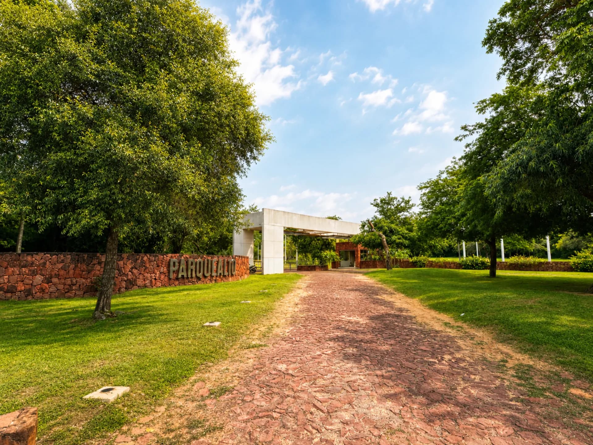 Entrada principal a Parquealto con cartel sobre muro de piedra